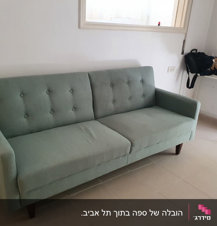 ספה ירוקה עם רגלי עץ בחדר ריק